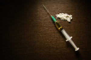 A syringe of heroin sits on a table